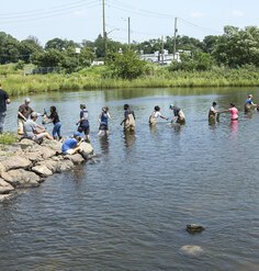 A line of students in waders and gloves pass bags down the line