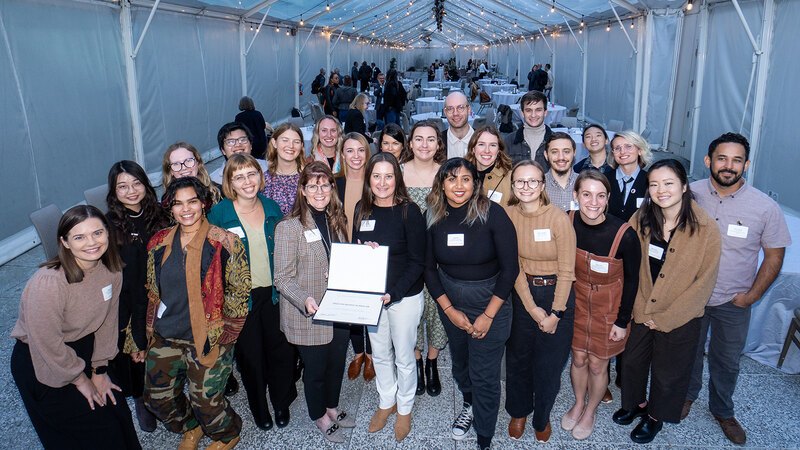 A group of Olmsted Scholars smiles while one holds a certificate