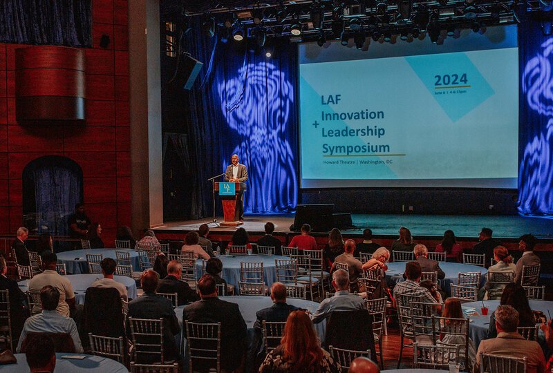 LAF President Michael Grove on stage behind a podium kicking off the symposium