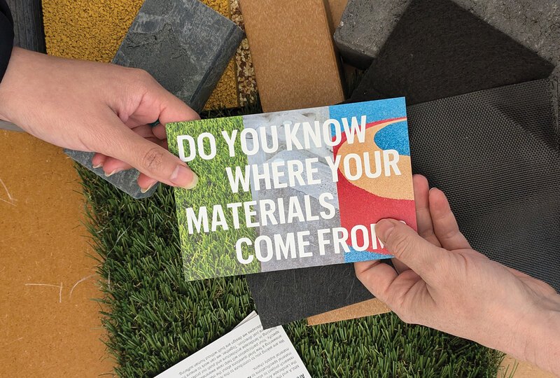 Two hands holding a postcard that says "Do you know where your materials come from?"