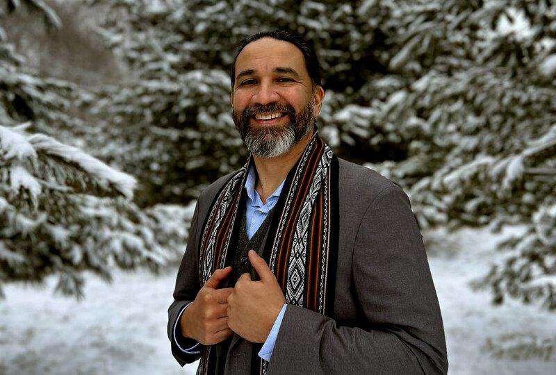 Headshot of Aiman Duckworth standing in front of snowy pine trees