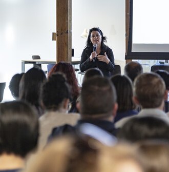 LAF CEO Barbara Deutsch holds a microphone and speaks to a large audience.