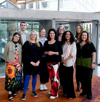9 members of the LAF staff stand smiling in a lobby