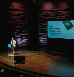 Roberto Rovira at a podium on a stage kicking off the 2023 symposium