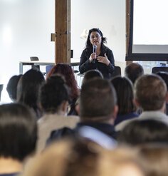 LAF CEO Barbara Deutsch holds a microphone and speaks to a large audience.