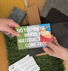 Two hands holding a postcard that says "Do you know where your materials come from?"