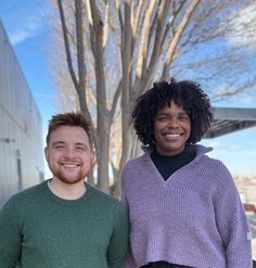 two staff pose outdoors in front of a tree